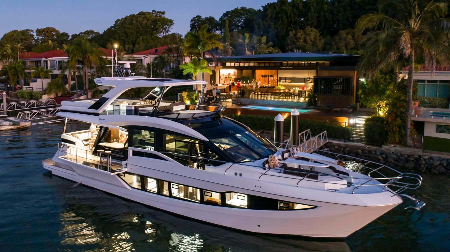 Galeon 640 Fly slipped at a residential dock at dusk with the salon and flybridge lit