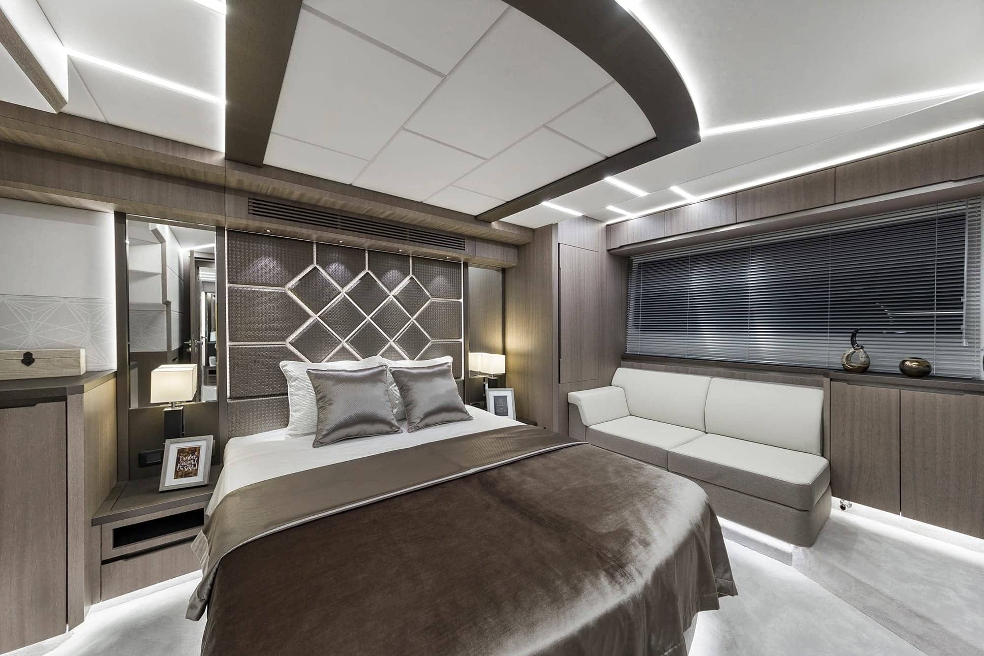 Master stateroom — king berth with diamond-quilted headboard, sofa, and full-width hull windows