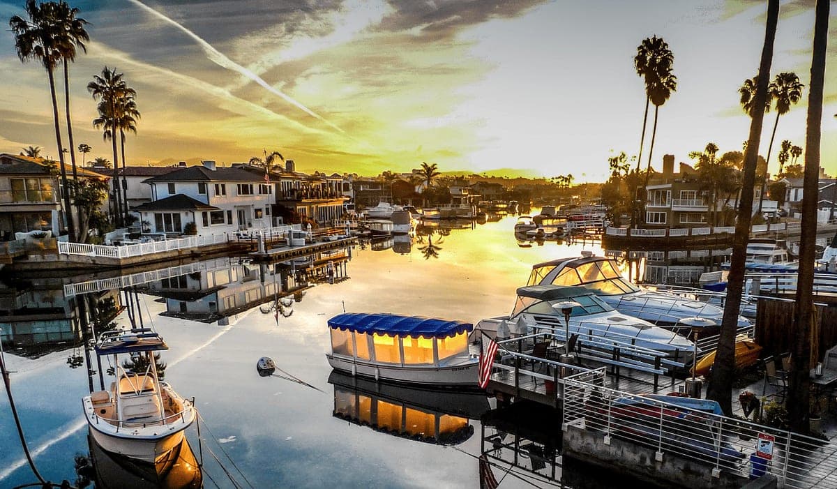 Yachts moored at Newport Beach marina with waterfront homes lining the harbor